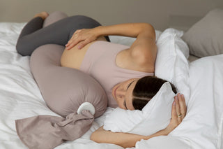 woman on bed sleeping with a pregnancy pillow