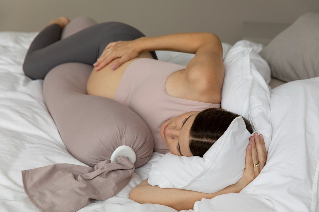 woman on bed sleeping with a pregnancy pillow