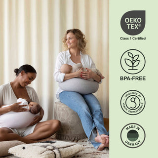 Two women breastfeeding their babies with Oeko-Tex, BPA-free bbhugme nursing pillows, and Made in Germany certification logos on the right.